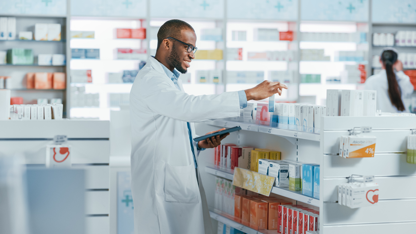 pharmacy: portrait of professional black pharmacist uses digital tablet computer, checks inventory of medicine, drugs, vitamins, health care products. druggist in drugstore store.